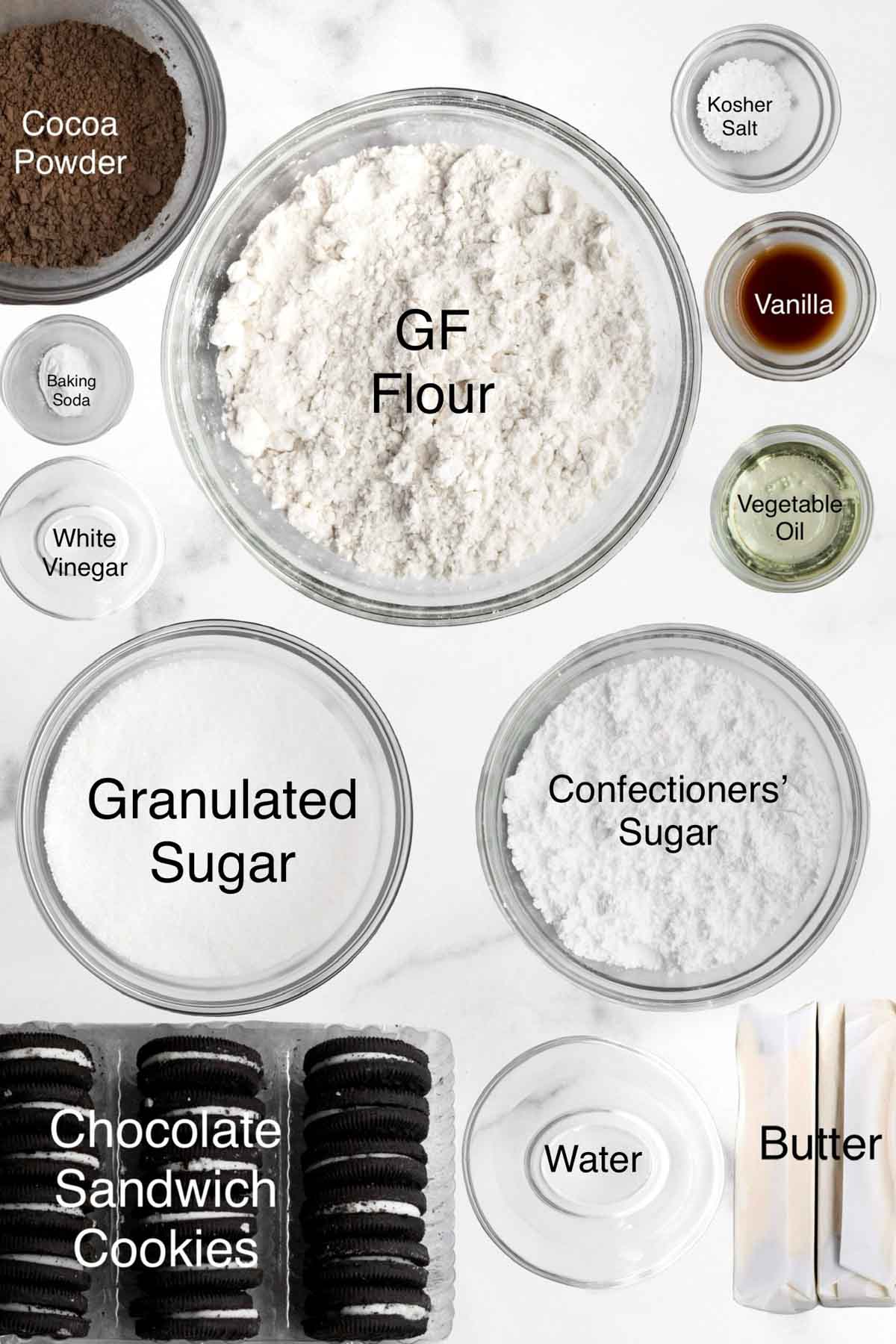 Cocoa powder, baking soda, white vinegar, gluten free flour, kosher salt, vanilla, vegetable oil, granulated sugar, confectioners' sugar, chocolate sandwich cookies, water and butter in separate containers.