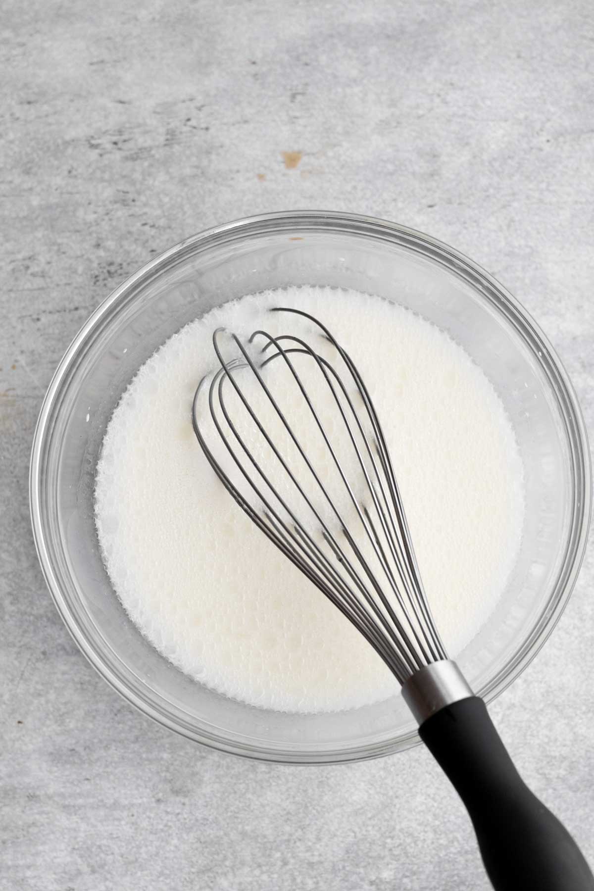 A whisk with the white wet ingredients.