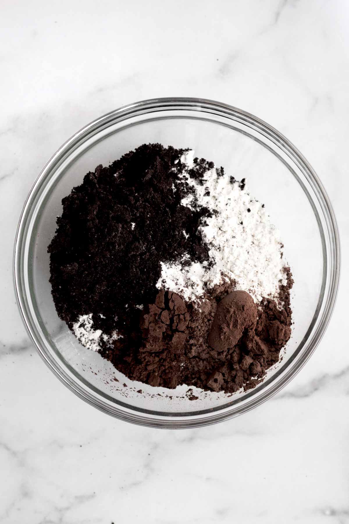 The unmixed black, brown and white dry ingredients in a glass bowl.