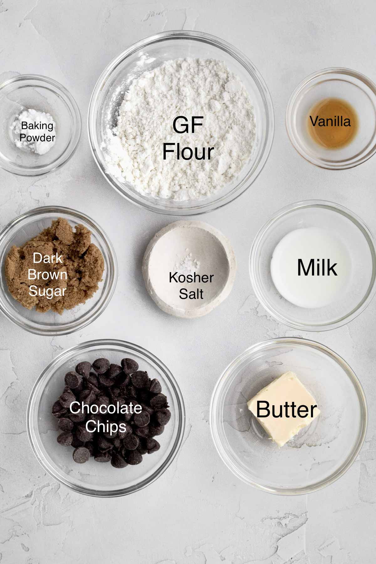 Baking powder, gluten free flour, vanilla, dark brown sugar, kosher salt, milk, chocolate chips and butter in separate containers.