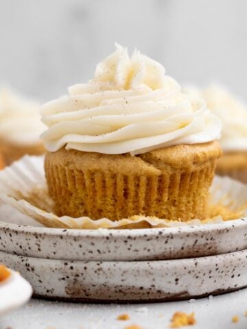 A perfect piped swirl of Cream Cheese Frosting sits in creamy goodness atop this pumpkin cupcake.