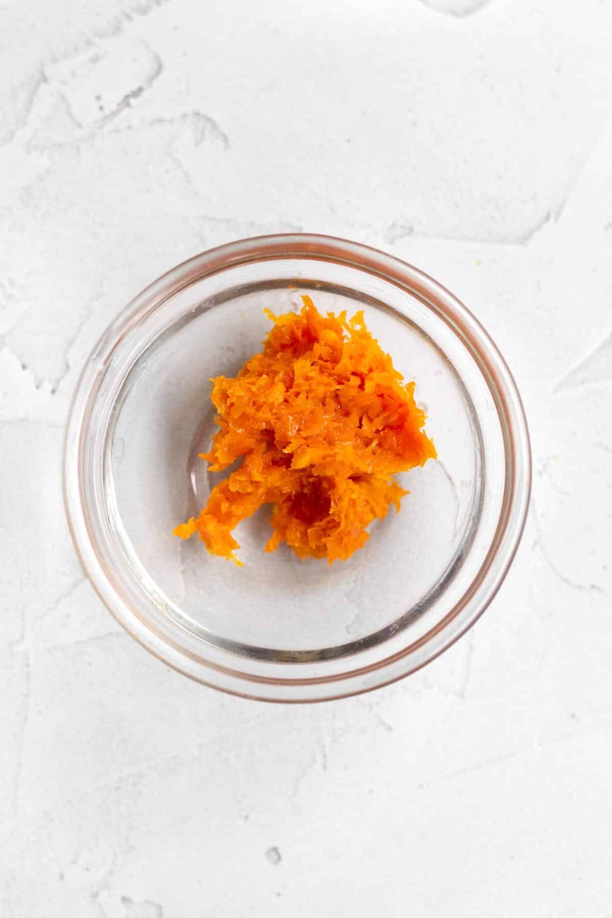 Bright orange zest of an orange in a glass bowl.