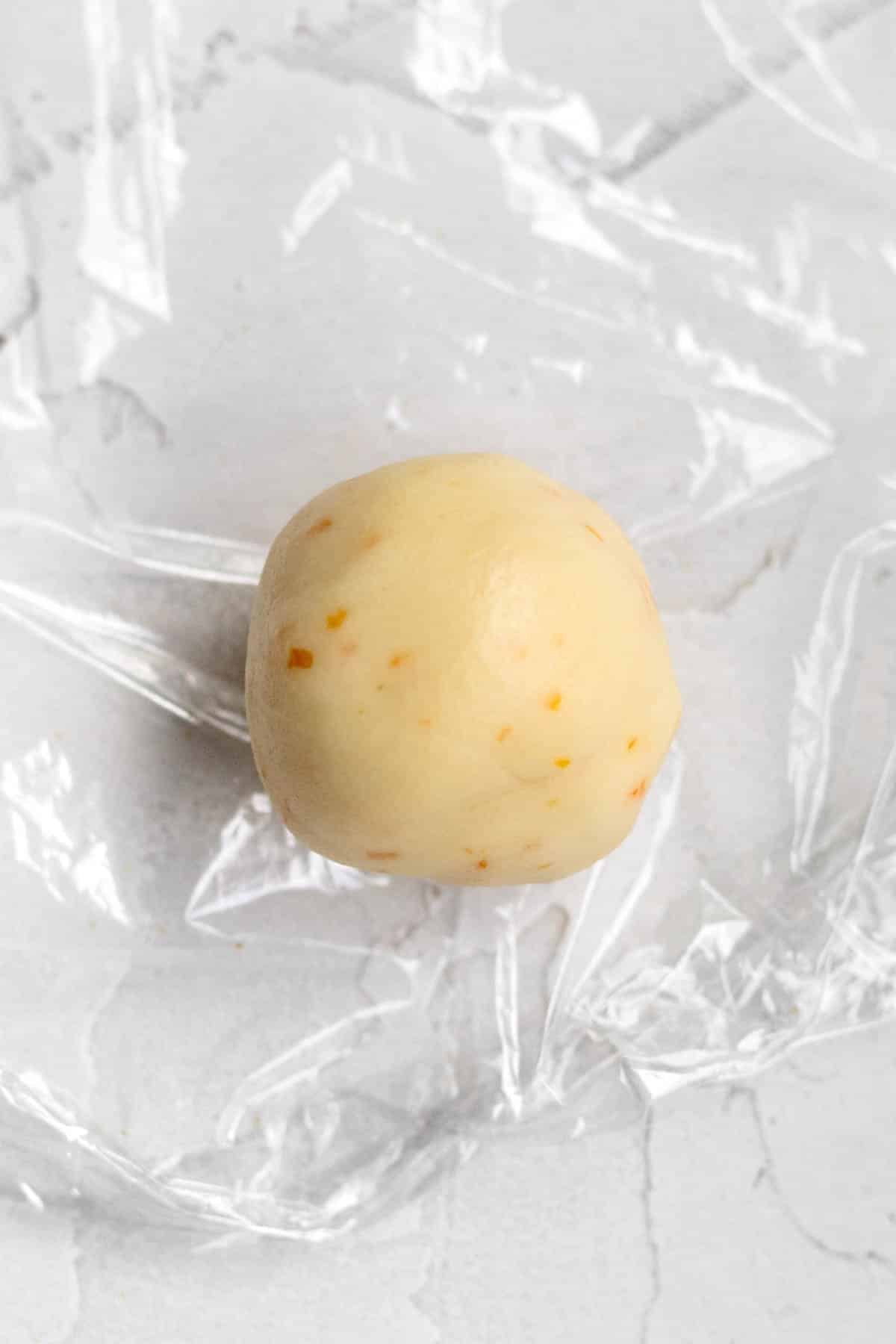 A scooped ball of Orange Shortbread Cookie Dough.