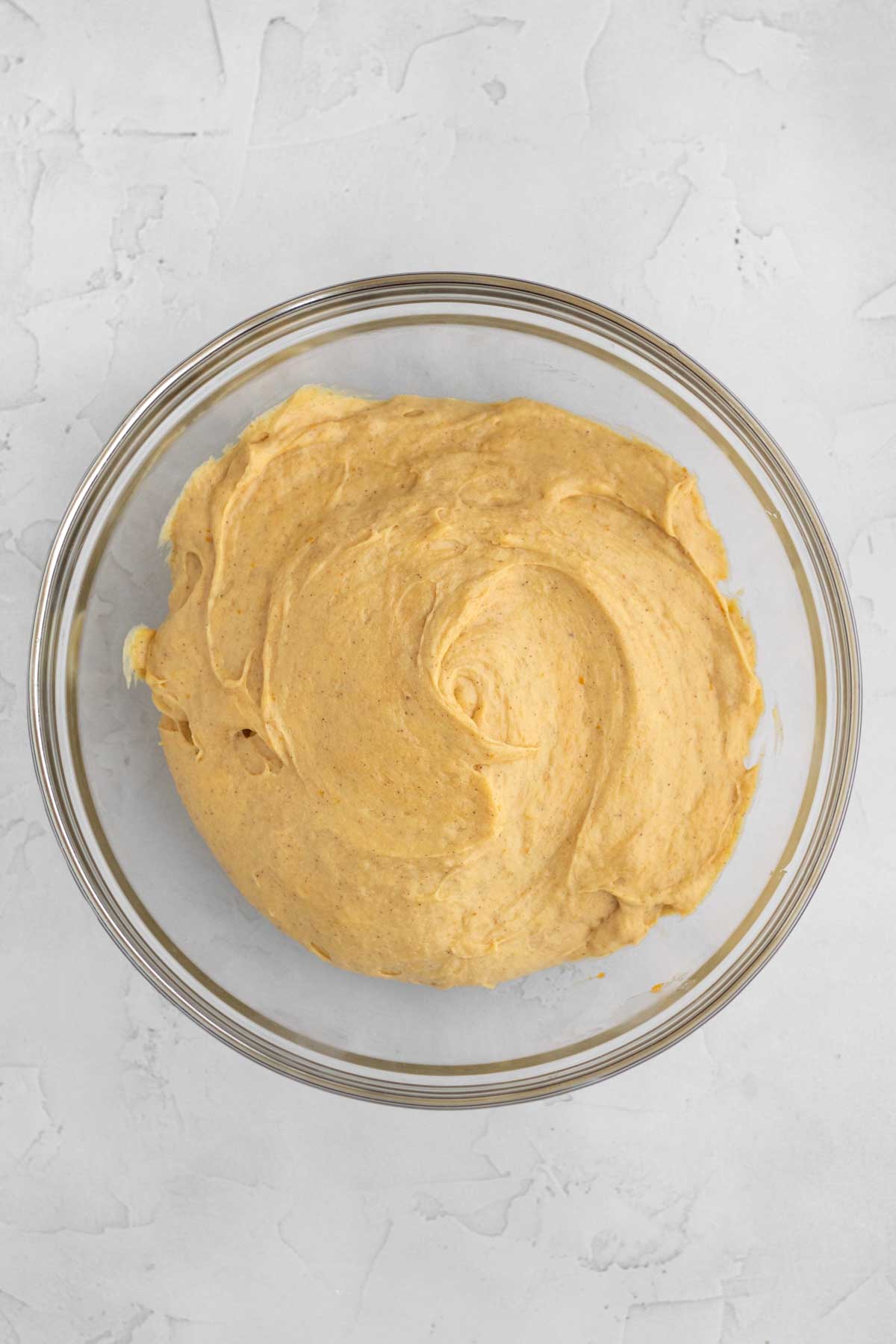 Adding milk and mixing into a smooth pumpkin cupcake batter.