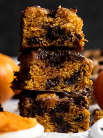 A stack of three delicious Chocolate Chip Pumpkin Bars with melted chips and warm pumpkin flavor.