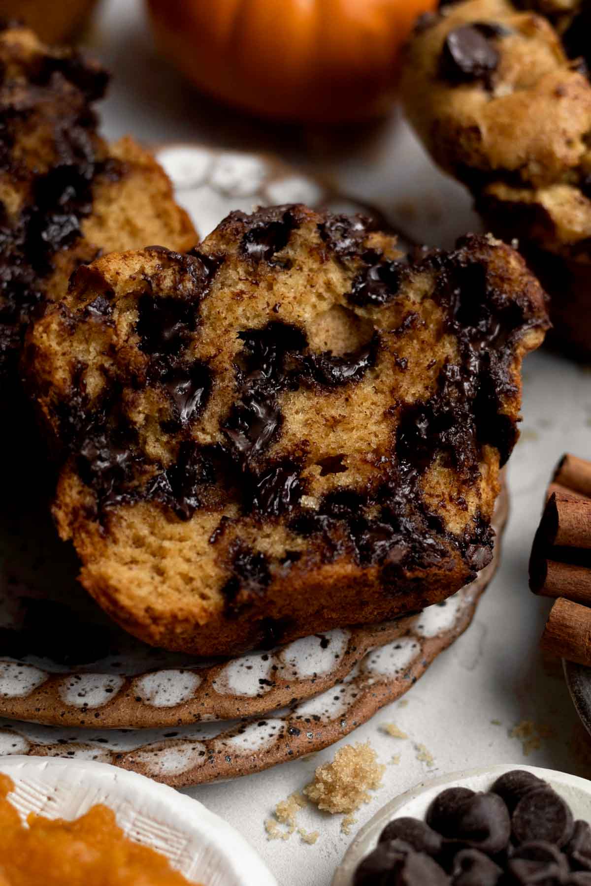 A sliced Gluten Free Pumpkin Muffin with its cozy pumpkin flavor and gooey chocolate chips.