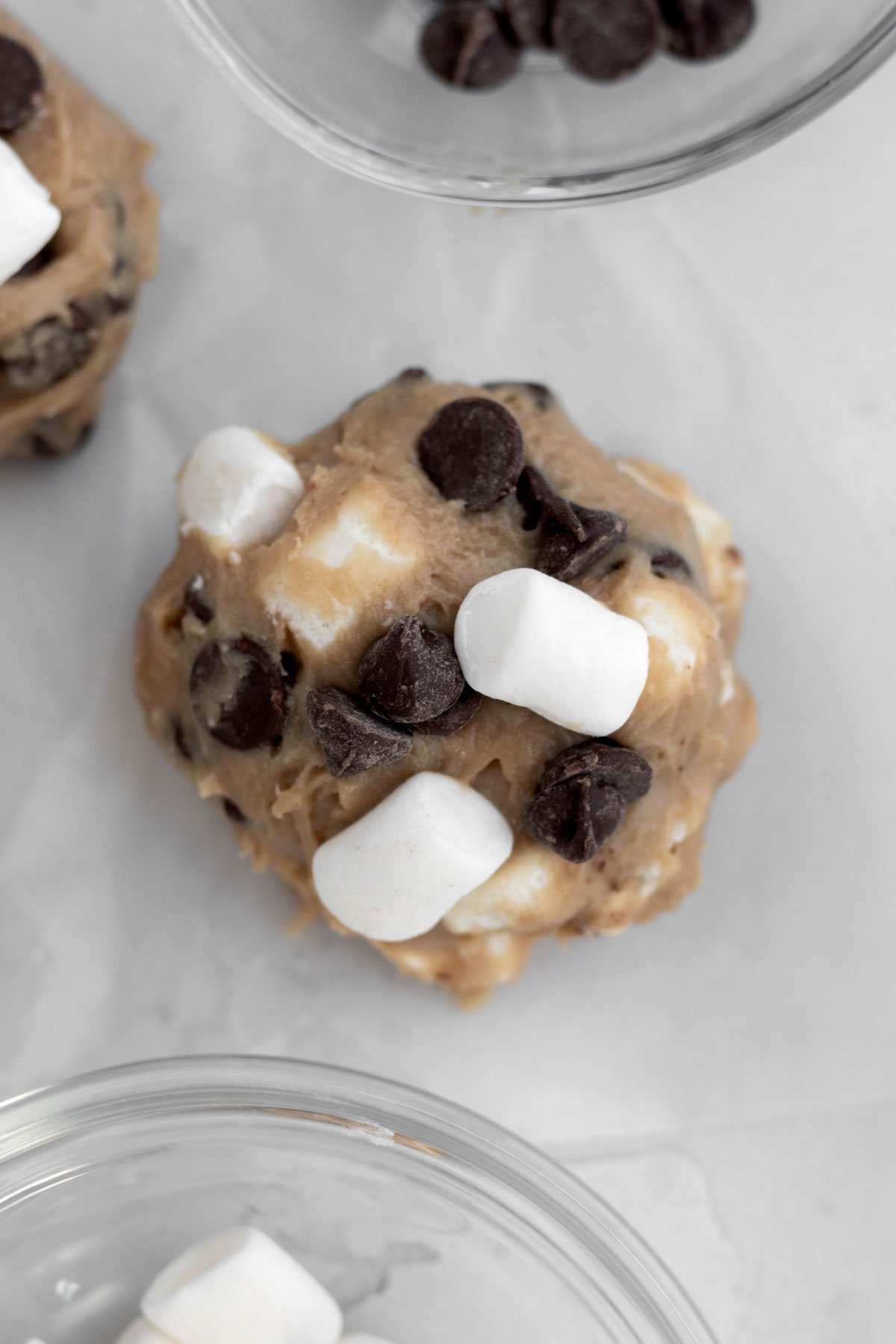 Pressing extra chocolate chips and marshmallows to the cookie dough ball.