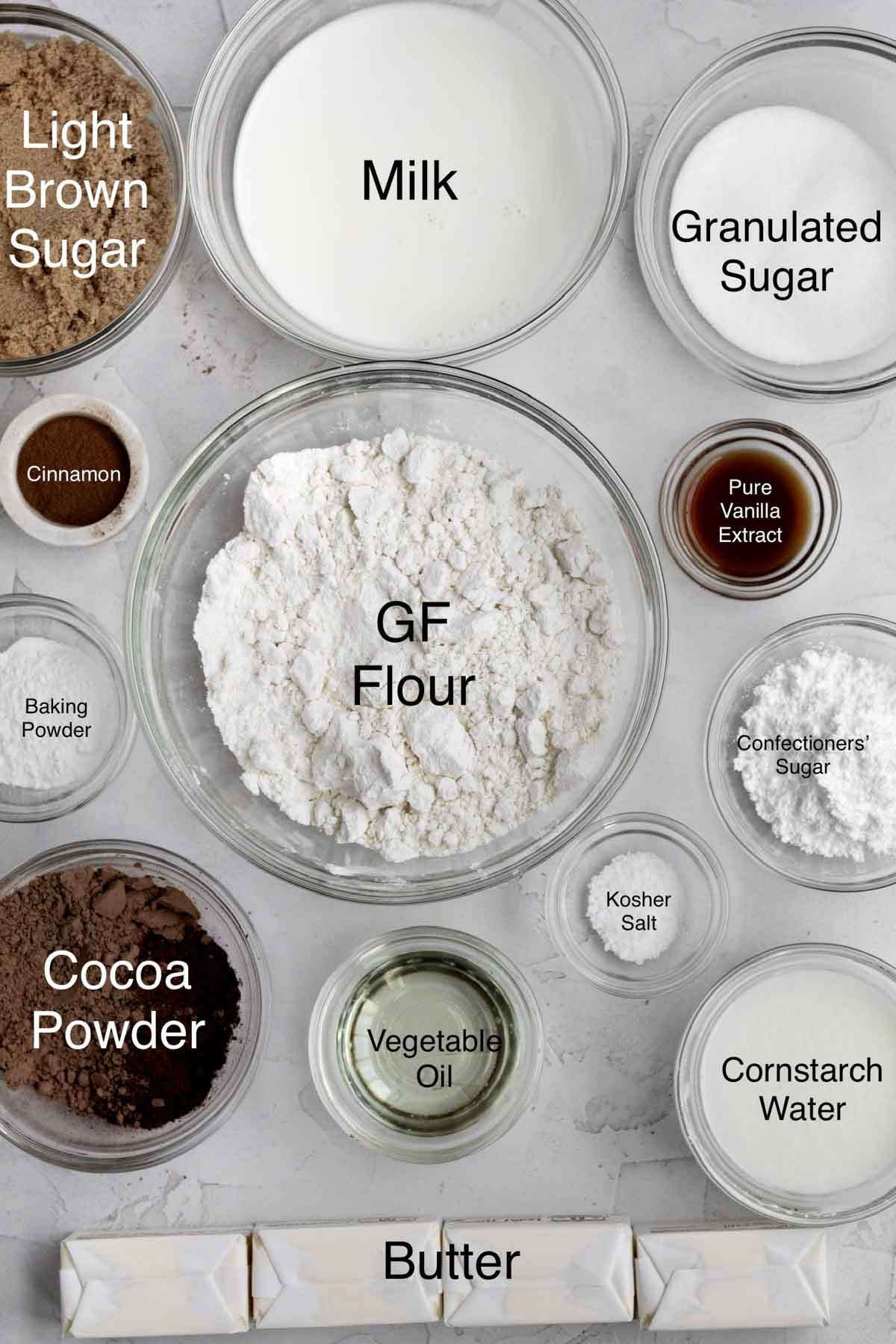Light brown sugar, milk, granulated sugar, cinnamon, gluten free flour, pure vanilla extract, baking powder, confectioners' sugar, cocoa powder, vegetable oil, kosher salt, cornstarch water and butter in separate containers.