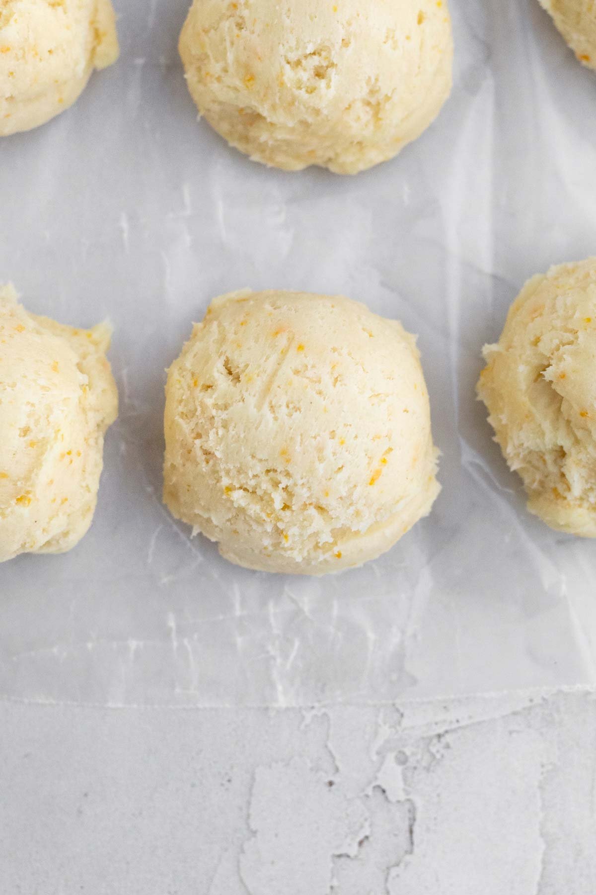Scooping balls of cookie dough with bright orange flecks in them.