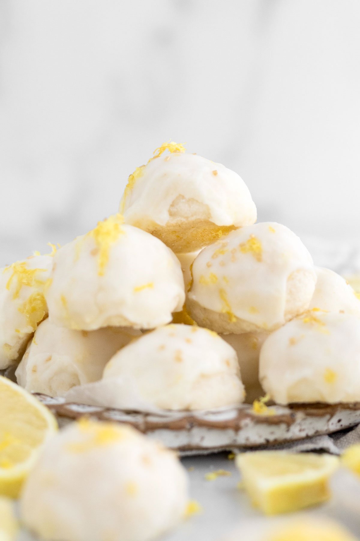 A plate overflowing with lemon glazed, sweet buttery balls of gluten free Lemon Shortbread Cookies.