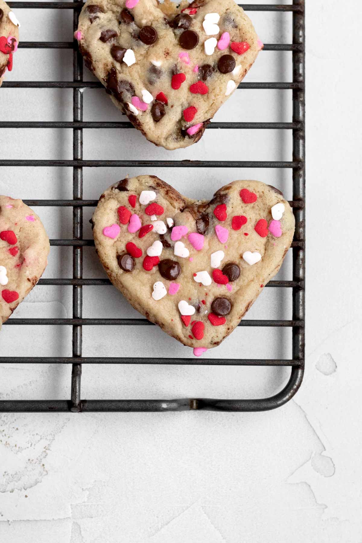 Warm and delicious Heart Shaped Chocolate Chip Cookies resting on a cooling rack.