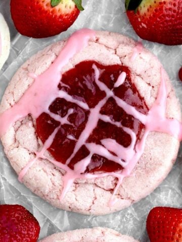 A Strawberry Jam Cookie with a sugary pink glaze drizzled over the delicious jam center.