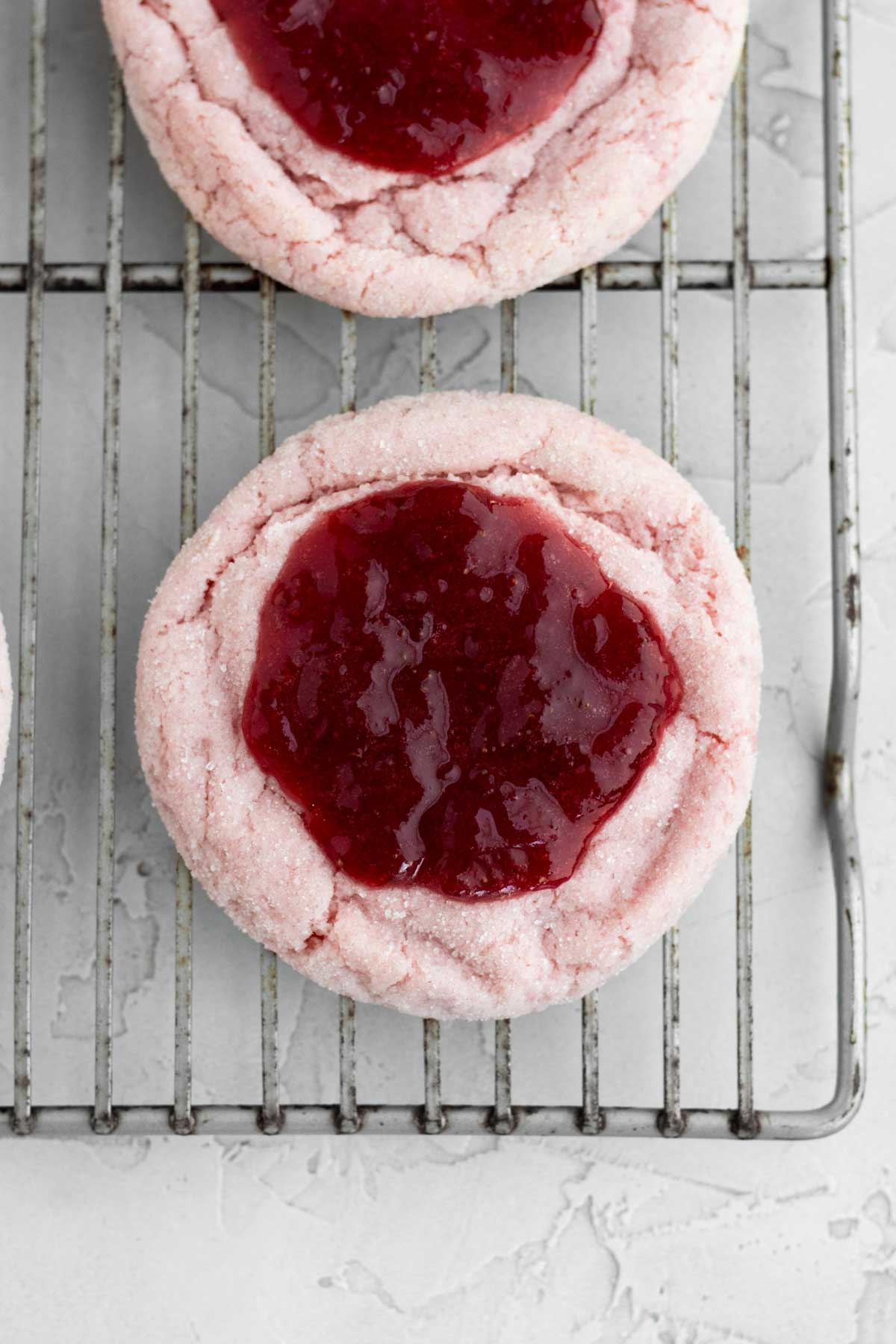 A round dollop of bright red strawberry jam is placed in the center of the cookie.