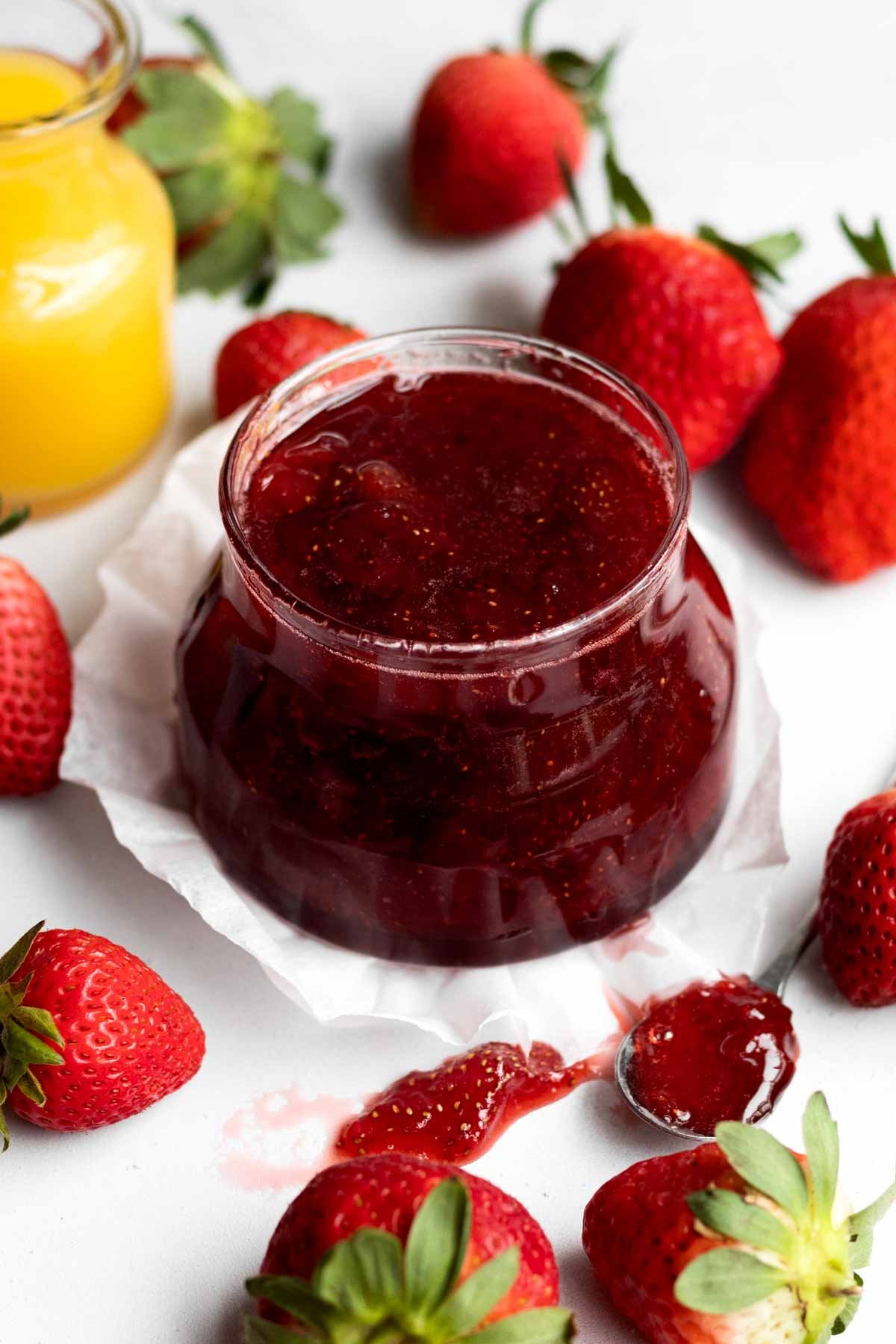 Delicious bright red sugary strawberry jam in a glass ramekin.