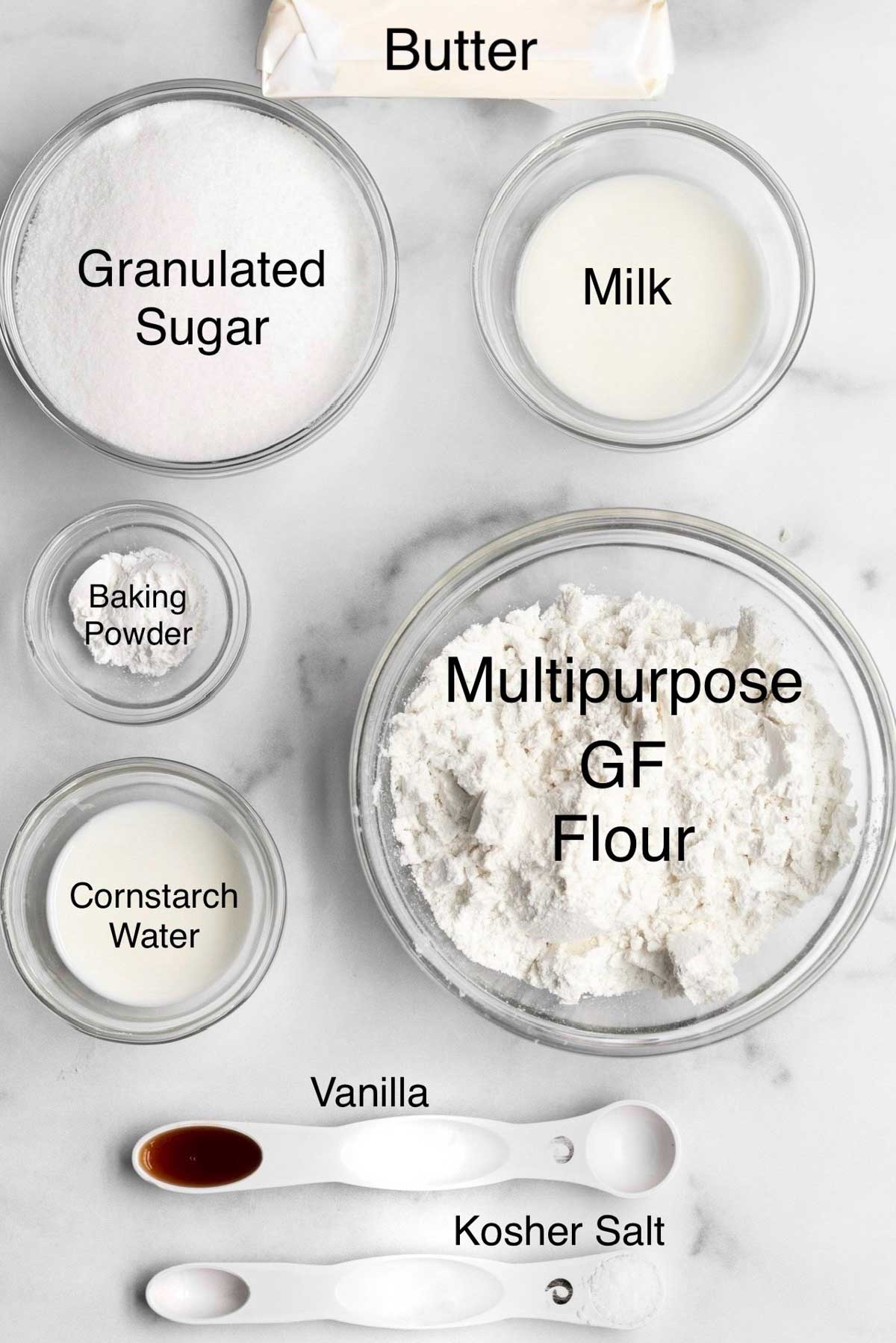 Separate containers of butter, granulated sugar, milk, baking powder, multipurpose gluten free flour, cornstarch water, vanilla and kosher salt.
