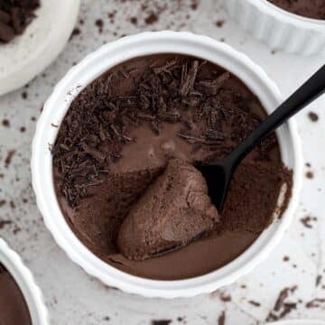 A tasteful bite of Easy Chocolate Mousse in a ramekin with shaved bits of chocolate.