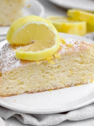 A light and delicious sugary slice of Lemon Tea Cake topped with a slice of lemon.