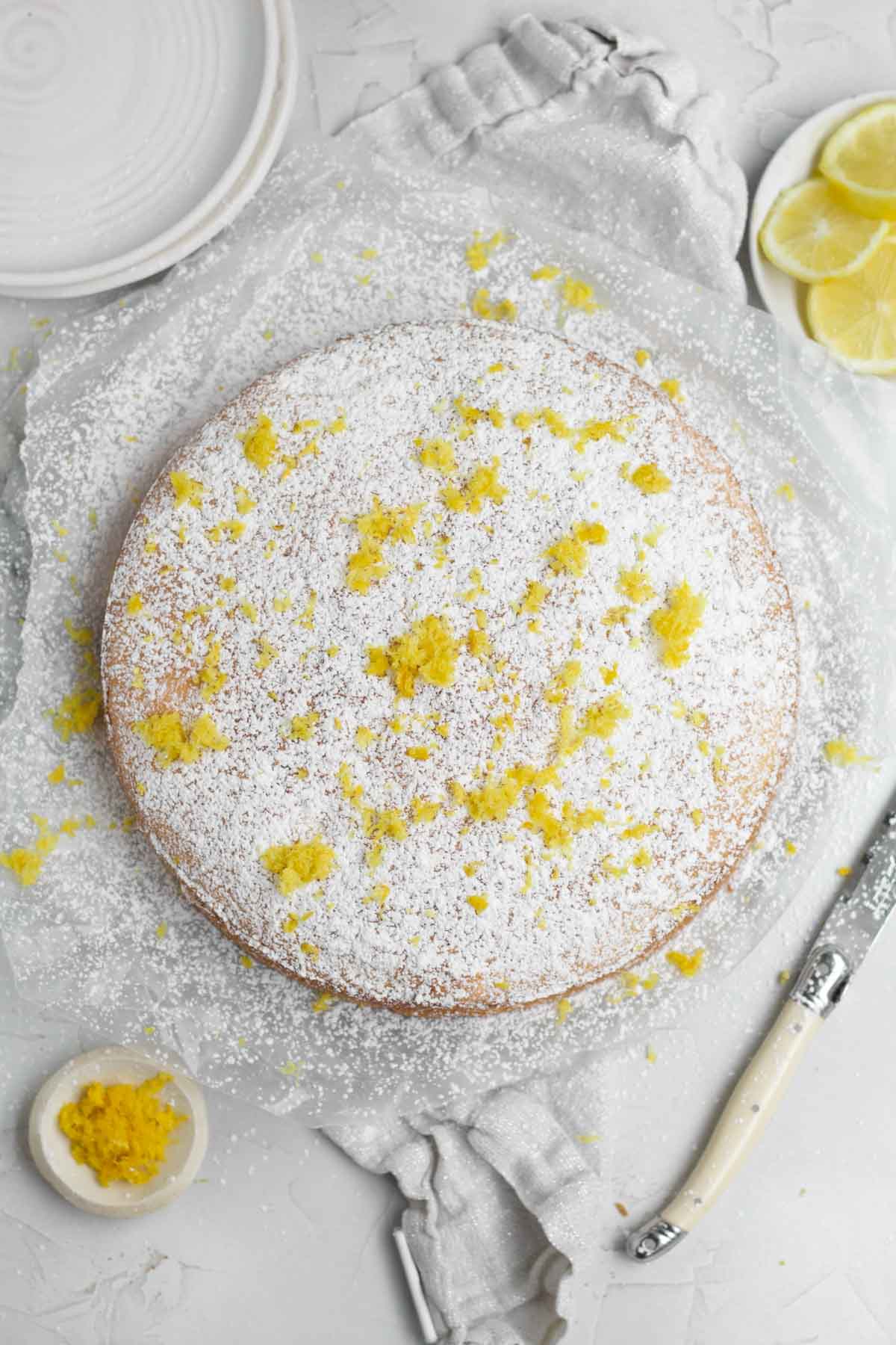 A flurry of powdered sugar blankets the top of the cake with flecks of lemon zest.