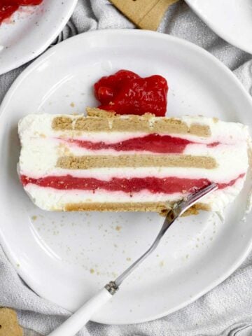 A layered slice of Strawberry Cream Cheese Icebox Cake with bright strawberry sauce filling.