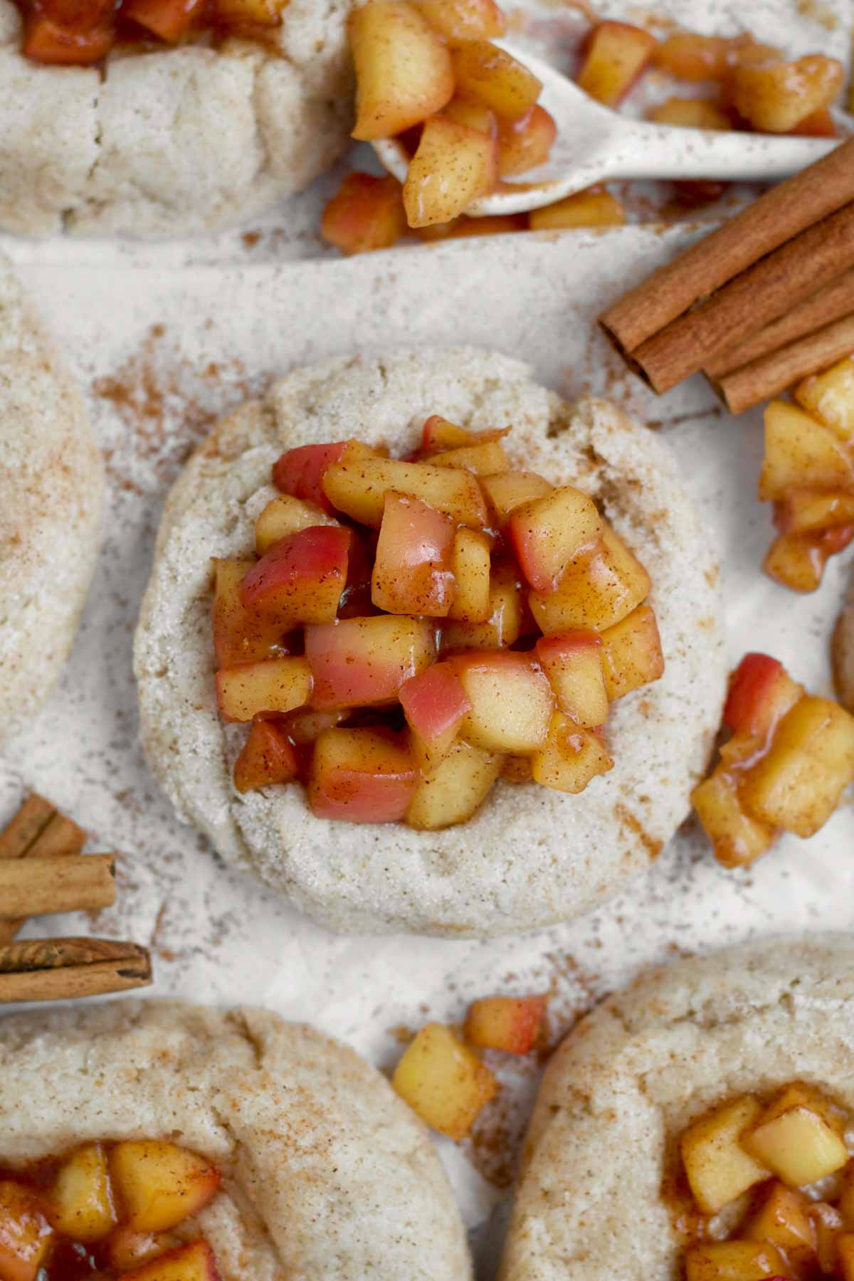 Cozy Apple Pie Cookies adorned with chopped red apples suspended in a sugary sauce.