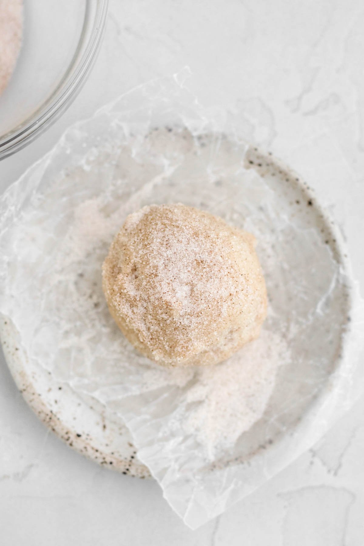 A scooped ball of Apple Pie Cookie dough covered in cinnamon sugar.