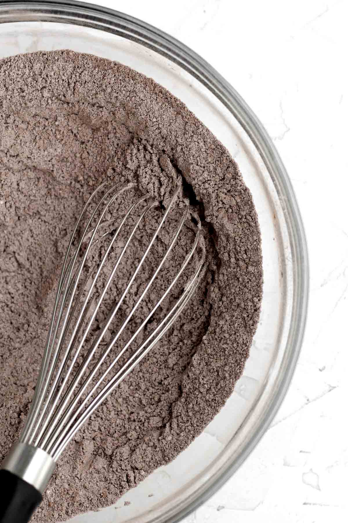 A whisk with mixed cocoa and dry ingredients.