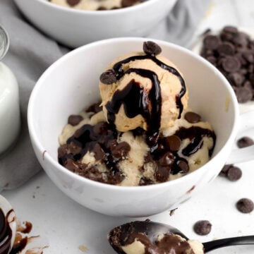 Soft, gooey mug cake featuring melted chocolate chips topped with delicious ice cream with rich chocolate sauce.