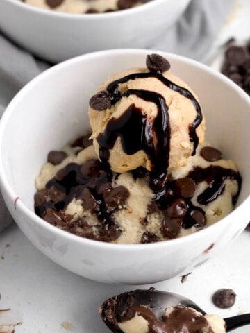 Soft, gooey mug cake featuring melted chocolate chips topped with delicious ice cream with rich chocolate sauce.