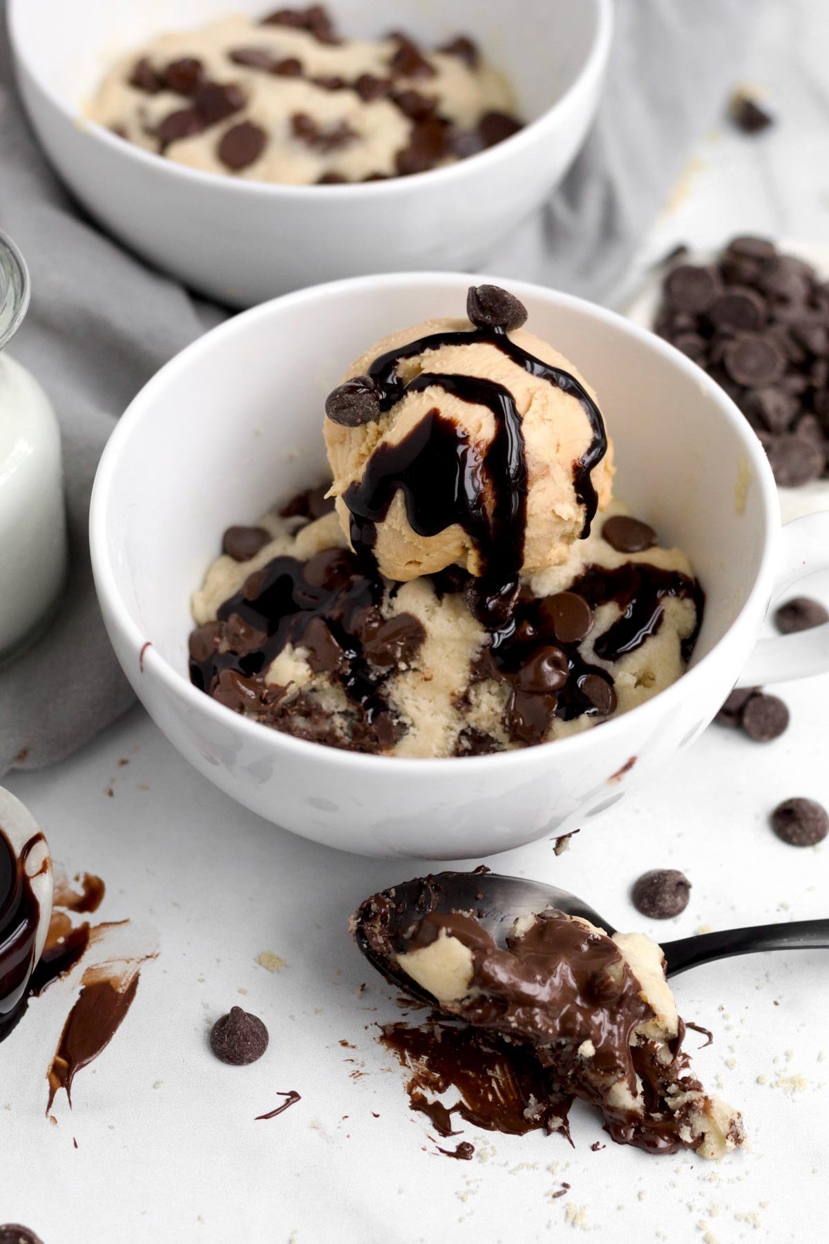 Soft, gooey mug cake featuring melted chocolate chips topped with delicious ice cream with rich chocolate sauce.
