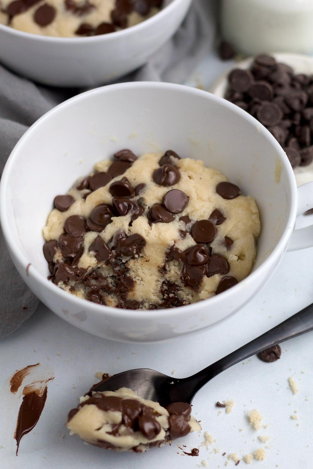 Freshly baked cookie mug cake with gooey chocolate chips with a healthy spoonful ready.