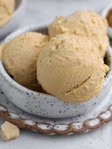 A rustic ceramic bowl filled with three perfect scoops of creamy peanut-free, "peanut butter" ice cream.