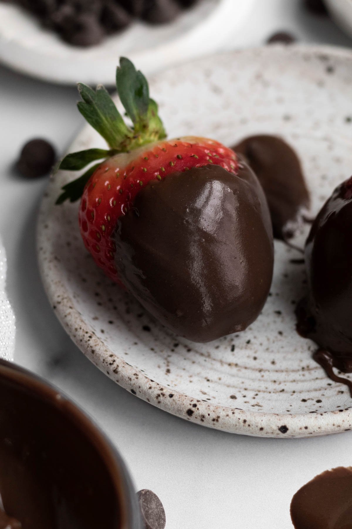 Hardened sugary chocolate ganache around a fresh red strawberry.