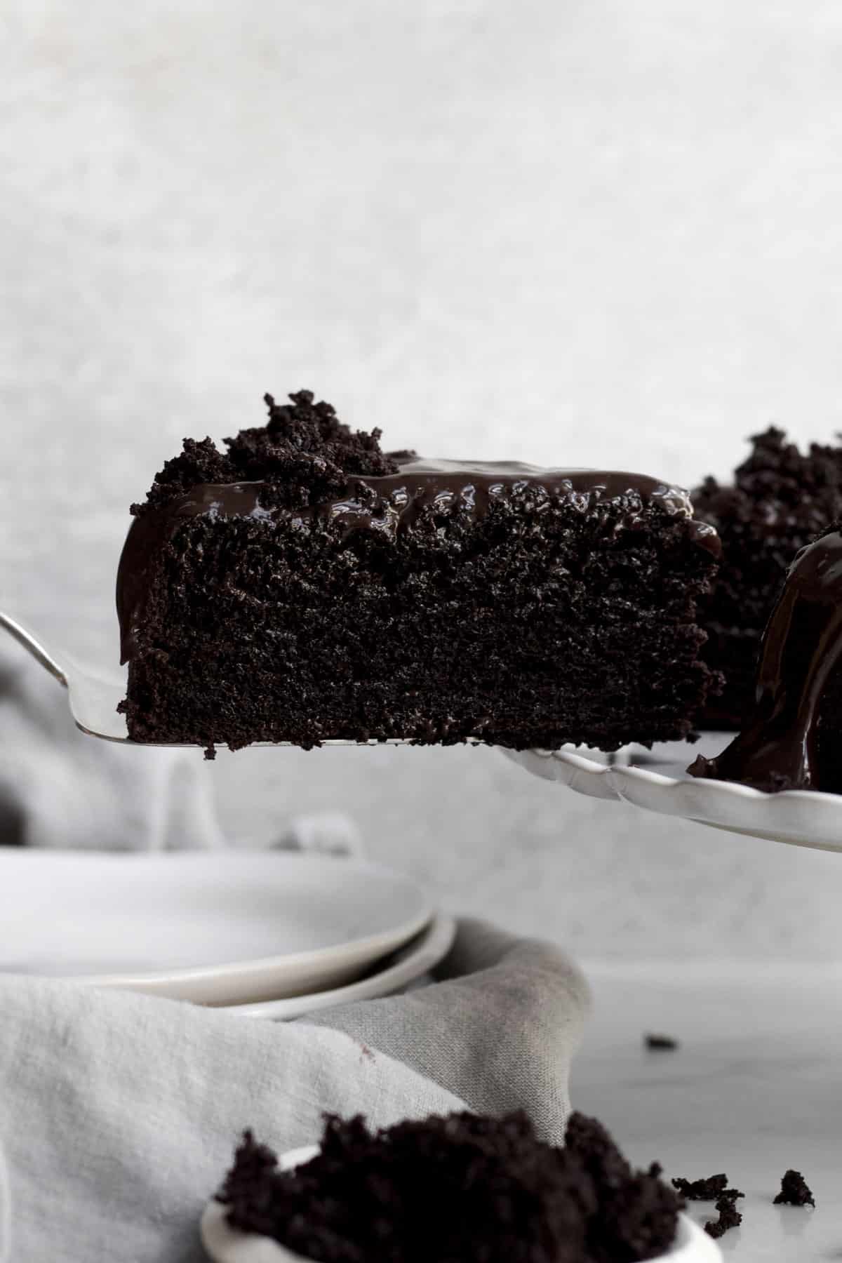 Rich dark chocolate ganache cake slice covered in silky chocolate glaze lifted from the cake.