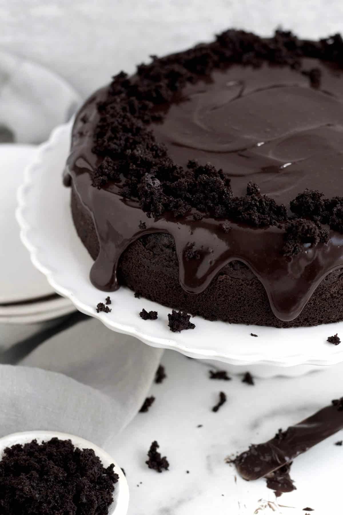 Chocolate cake with luscious ganache dripping down the sides with rich chocolate crumbles on a stand.