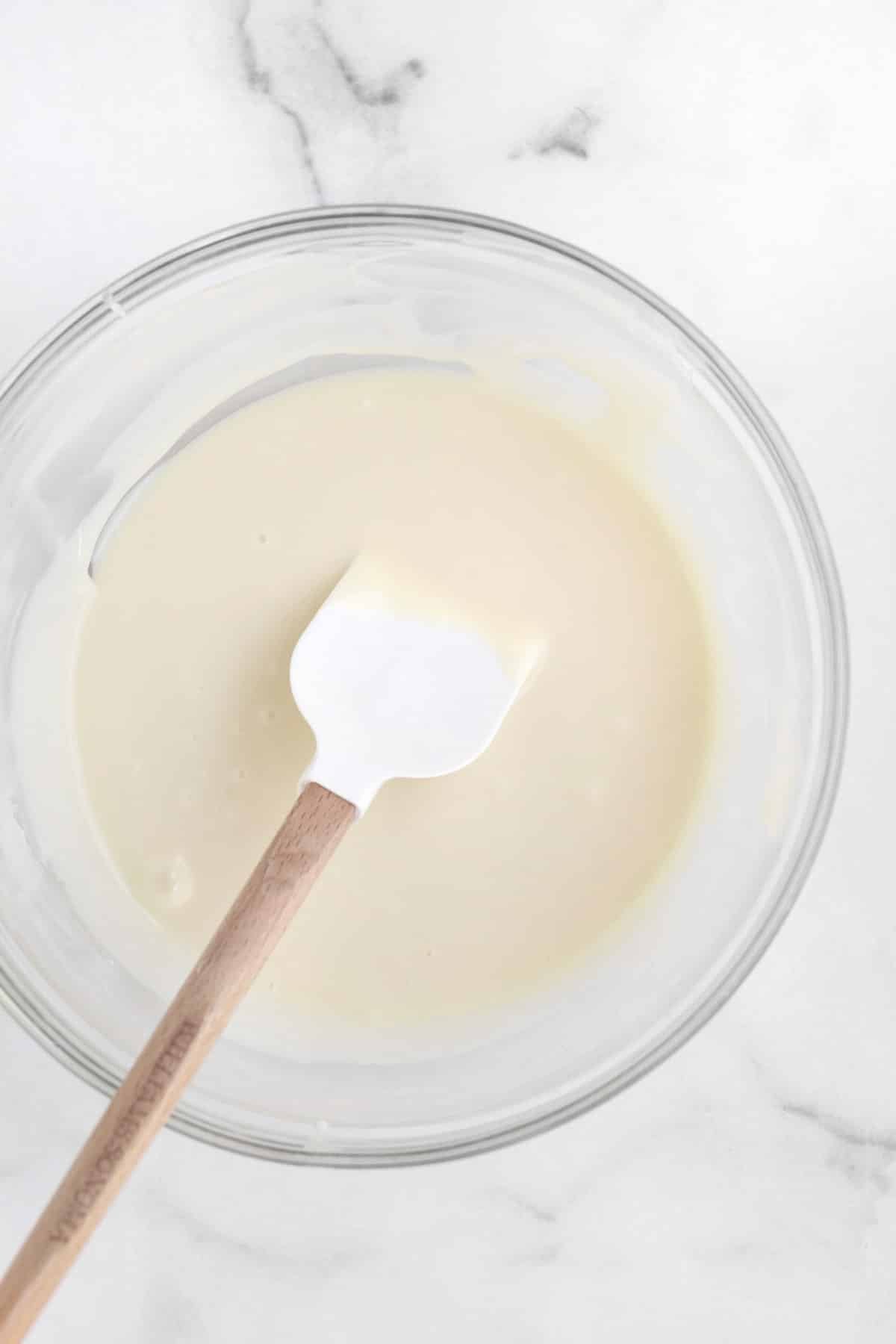 Rich, velvety and delicious white Chocolate Ganache in a bowl with a spatula.