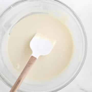 Rich, velvety and delicious white Chocolate Ganache in a bowl with a spatula.