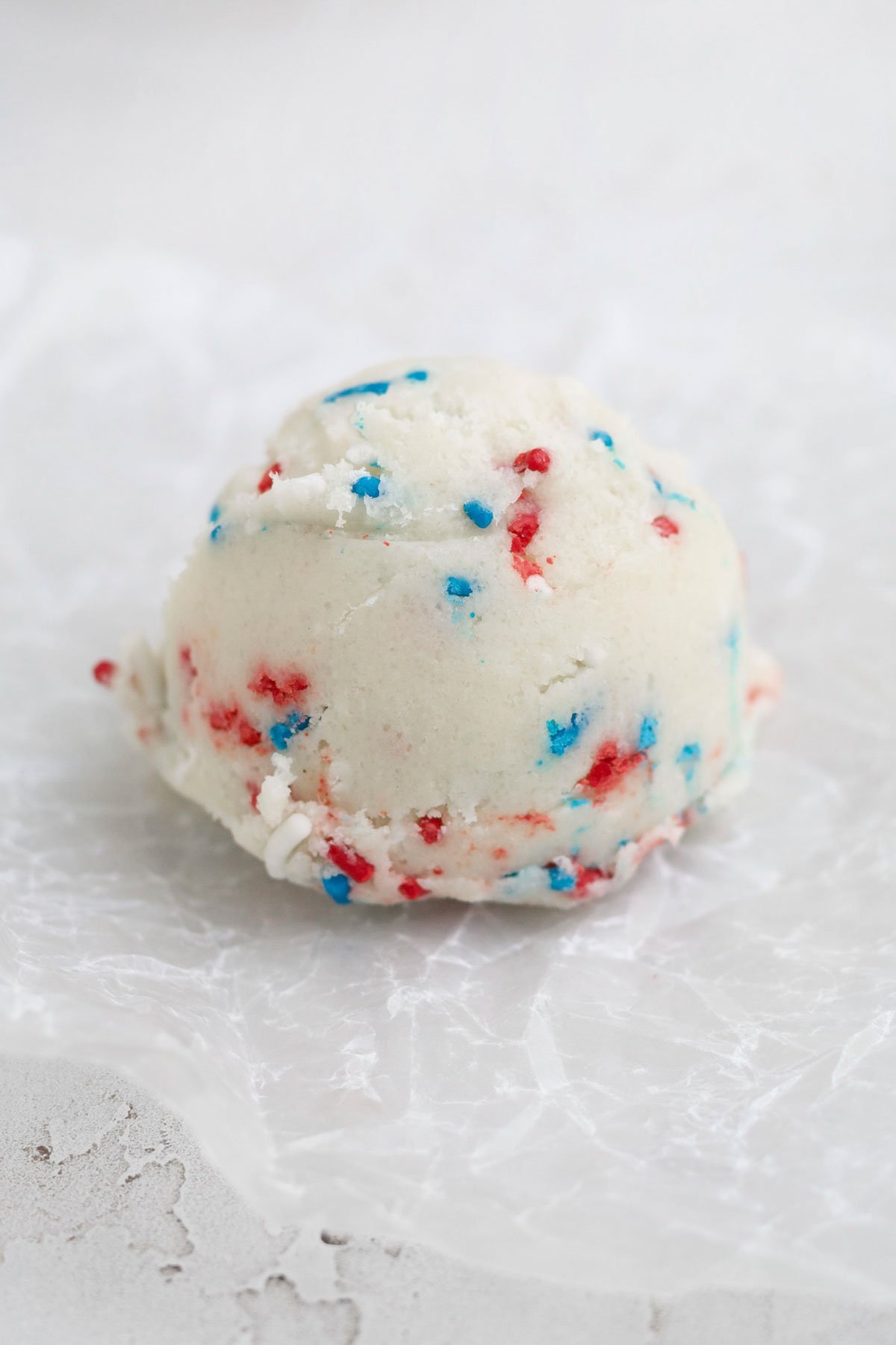 A scooped ball of red, white and blue sprinkle infused cookie dough.