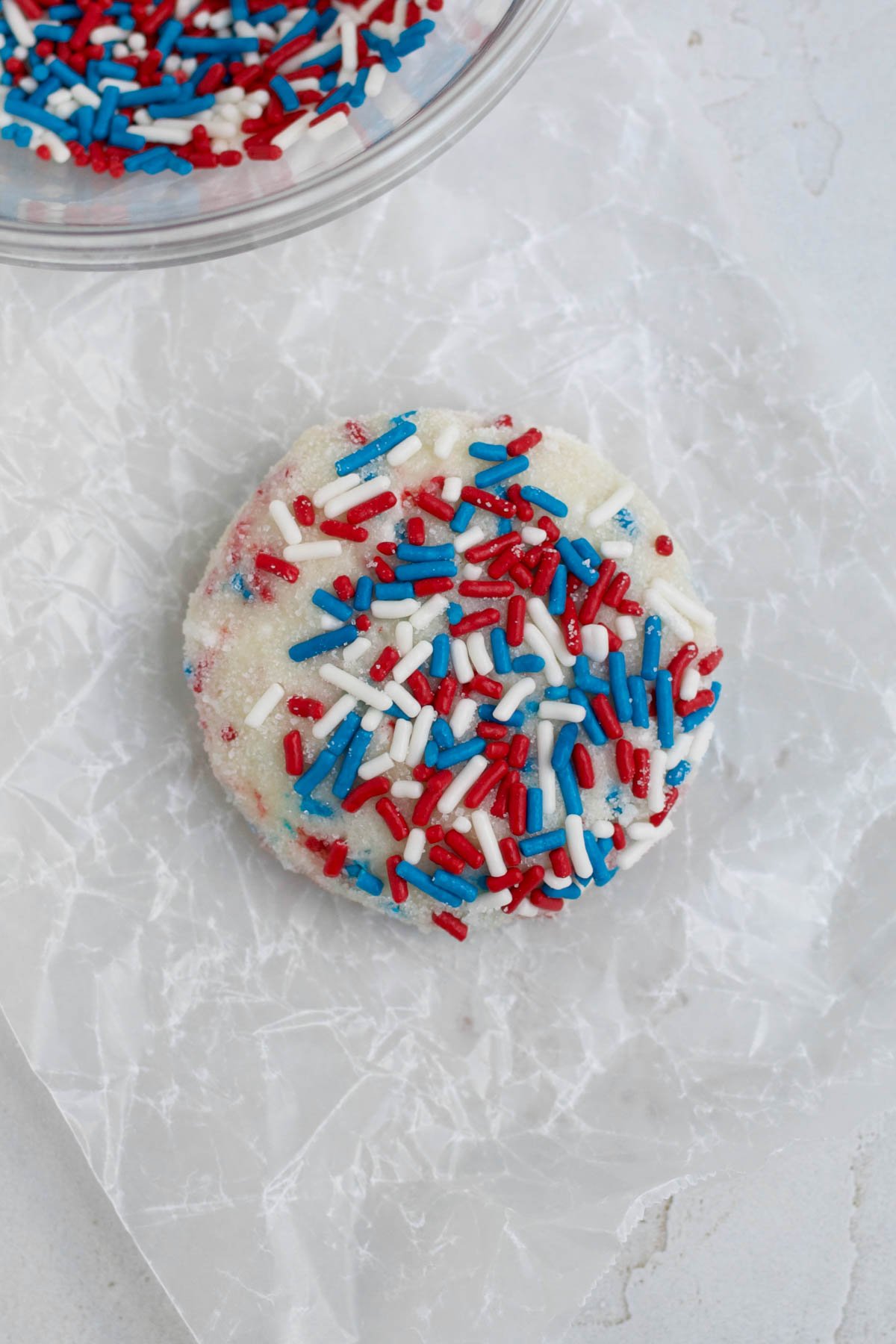 Pressing the dough ball flat and adding extra rod shaped sprinkles.