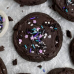 Lavender stars and purple and periwinkle rod sprinkles decorate the top of the frosted chocolate cookies.