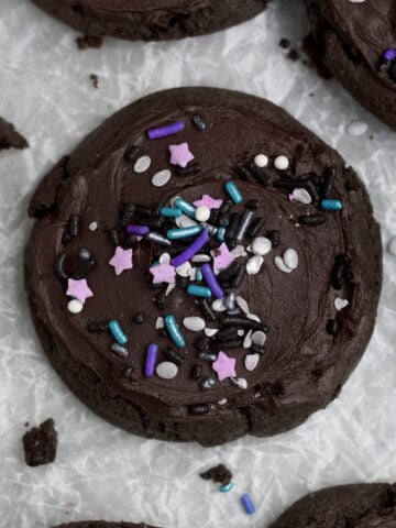 Lavender stars and purple and periwinkle rod sprinkles decorate the top of the frosted chocolate cookies.