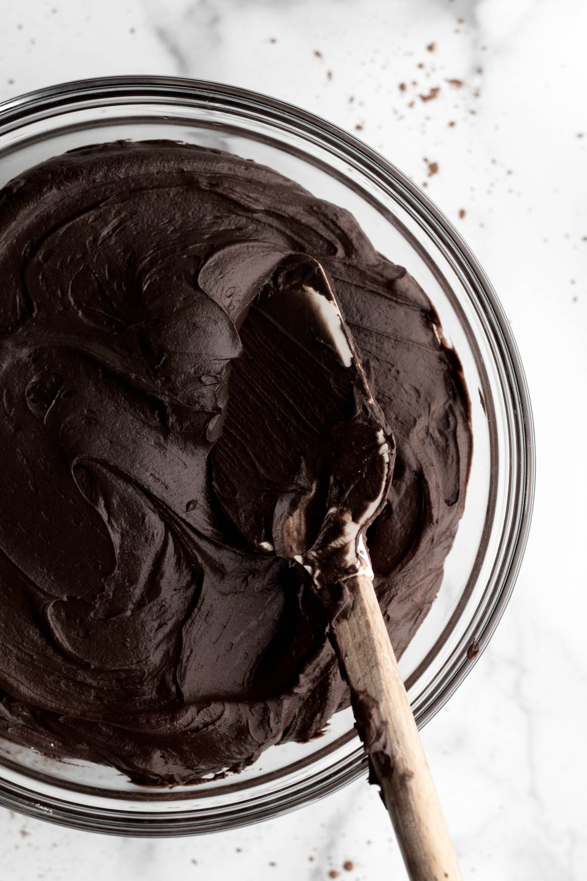 Rich creamy chocolate frosting in a bowl with a spatula.