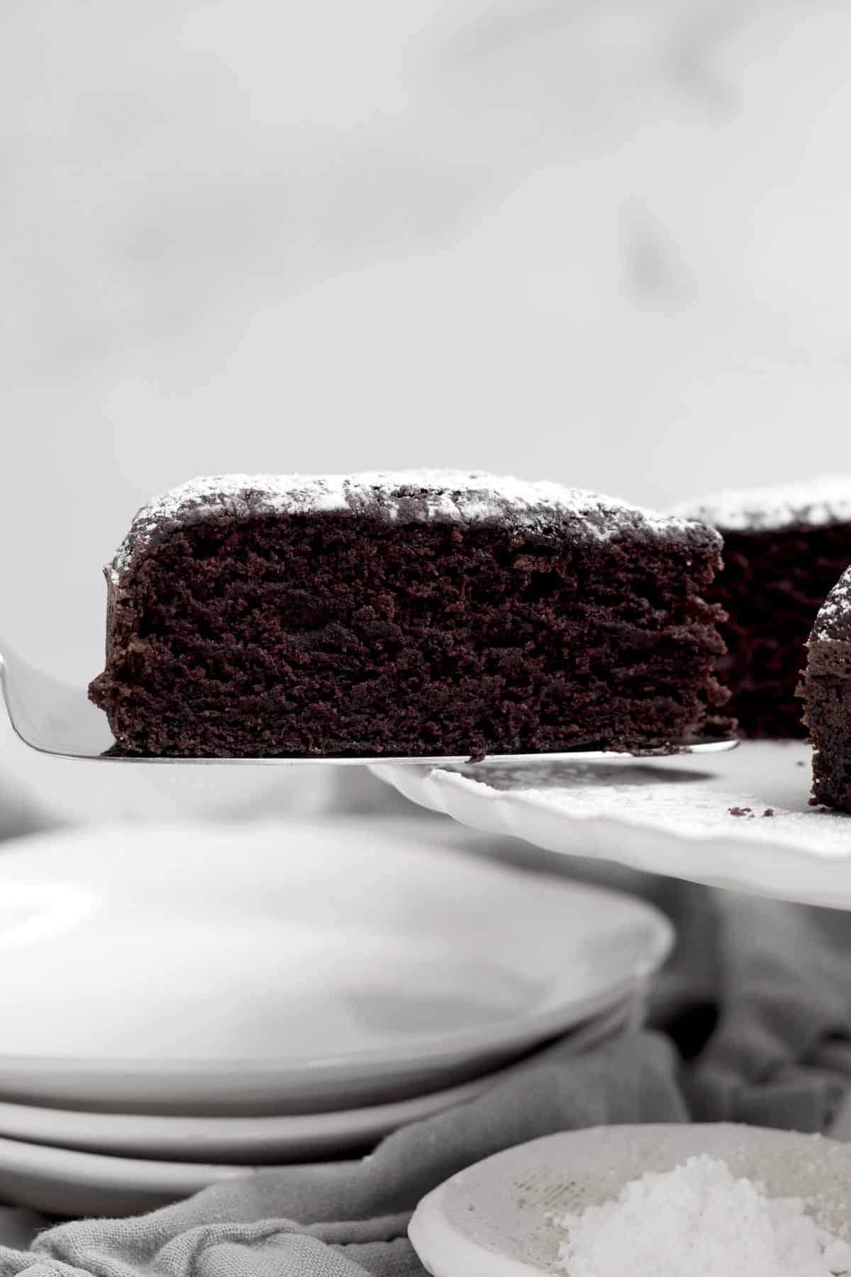 Taking a perfect slice of decadent chocolate olive oil cake from the whole.