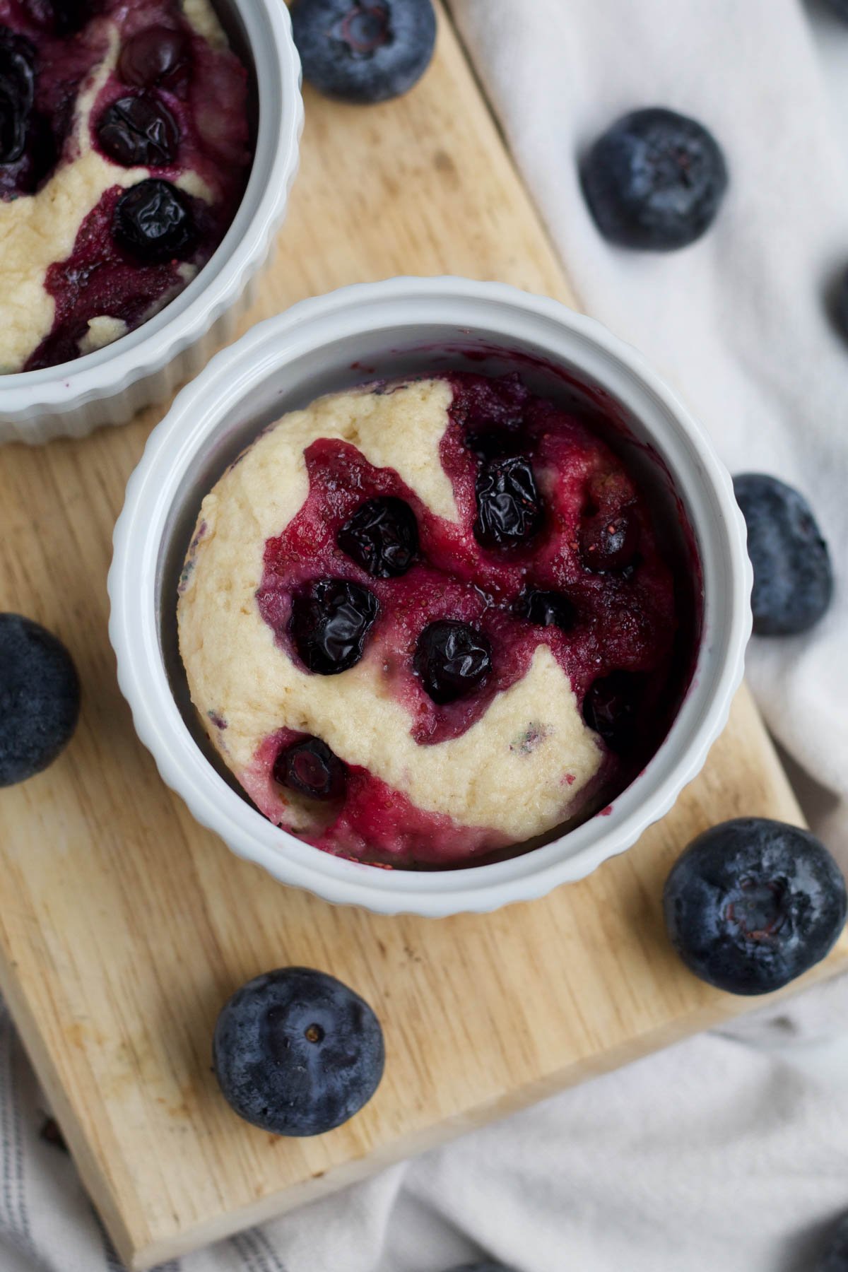 Baked blueberries stain the blueberry mug cakes a sweet magenta color.