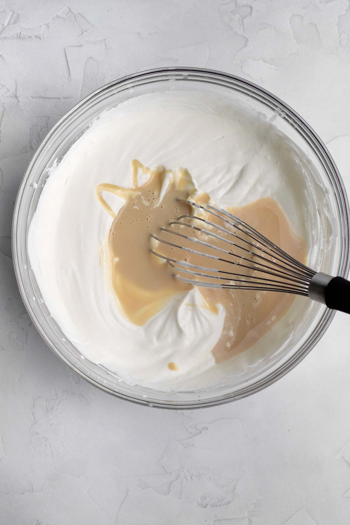 Adding the condensed milk mixture to the heavy cream.