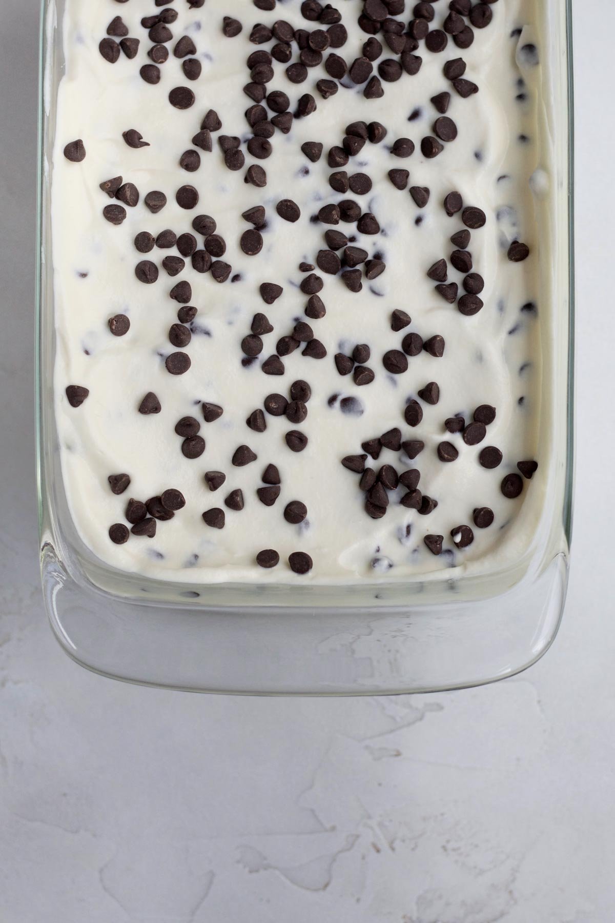 Filling a glass ice cream container and topping it with extra chocolate chips.