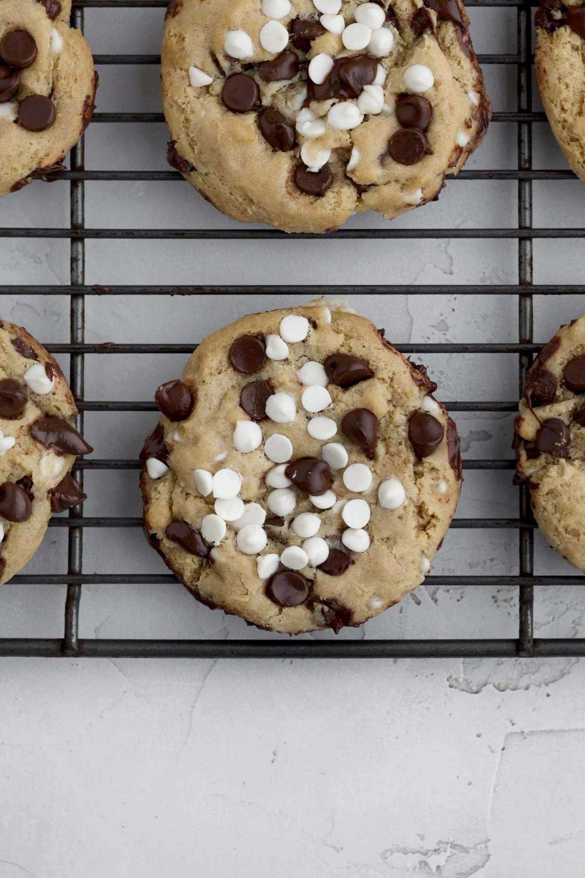 Fresh baked Chocolate Chip and White Chocolate Chip Cookies resting on a cooling rack.