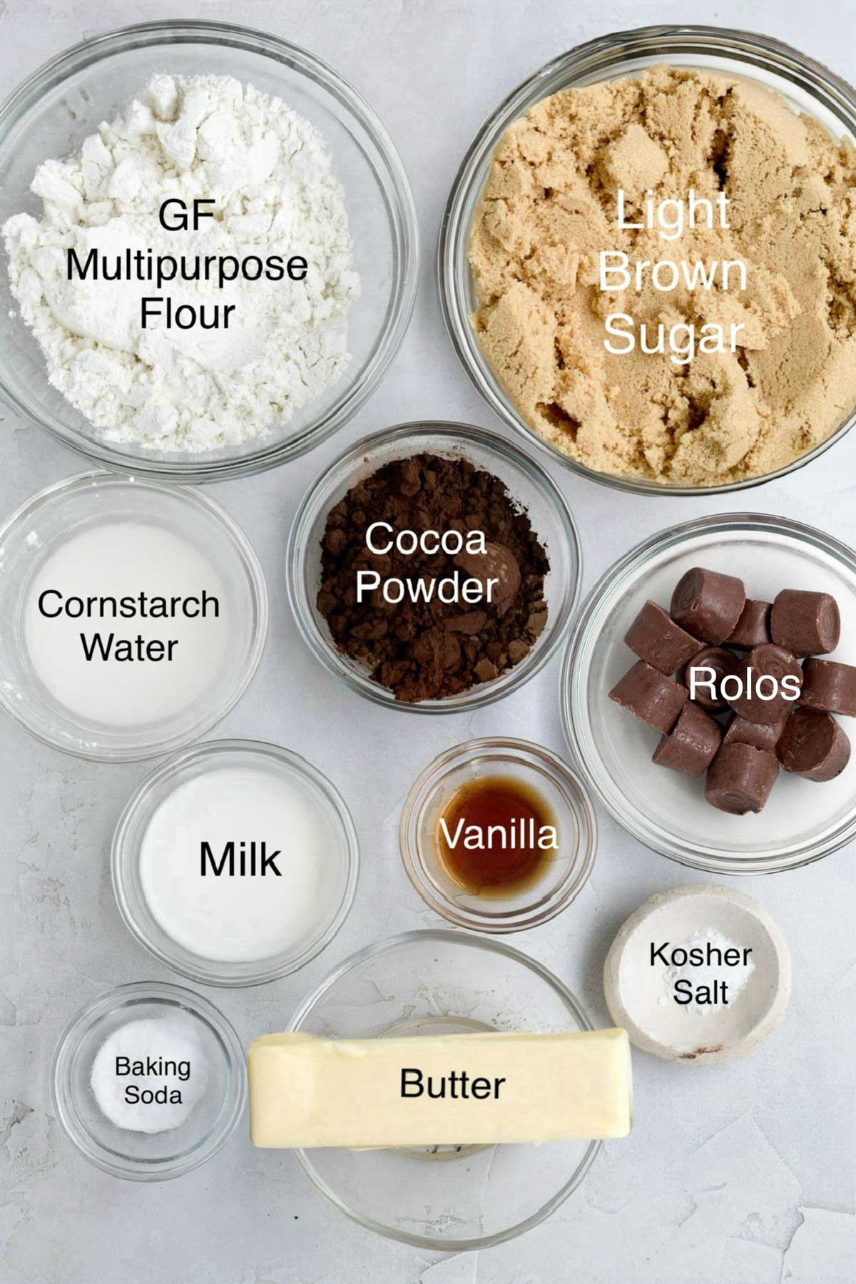 Bowls of gluten free flour, light brown sugar cornstarch water, cocoa powder, rolos, milk, vanilla, kosher salt, baking soda and butter.