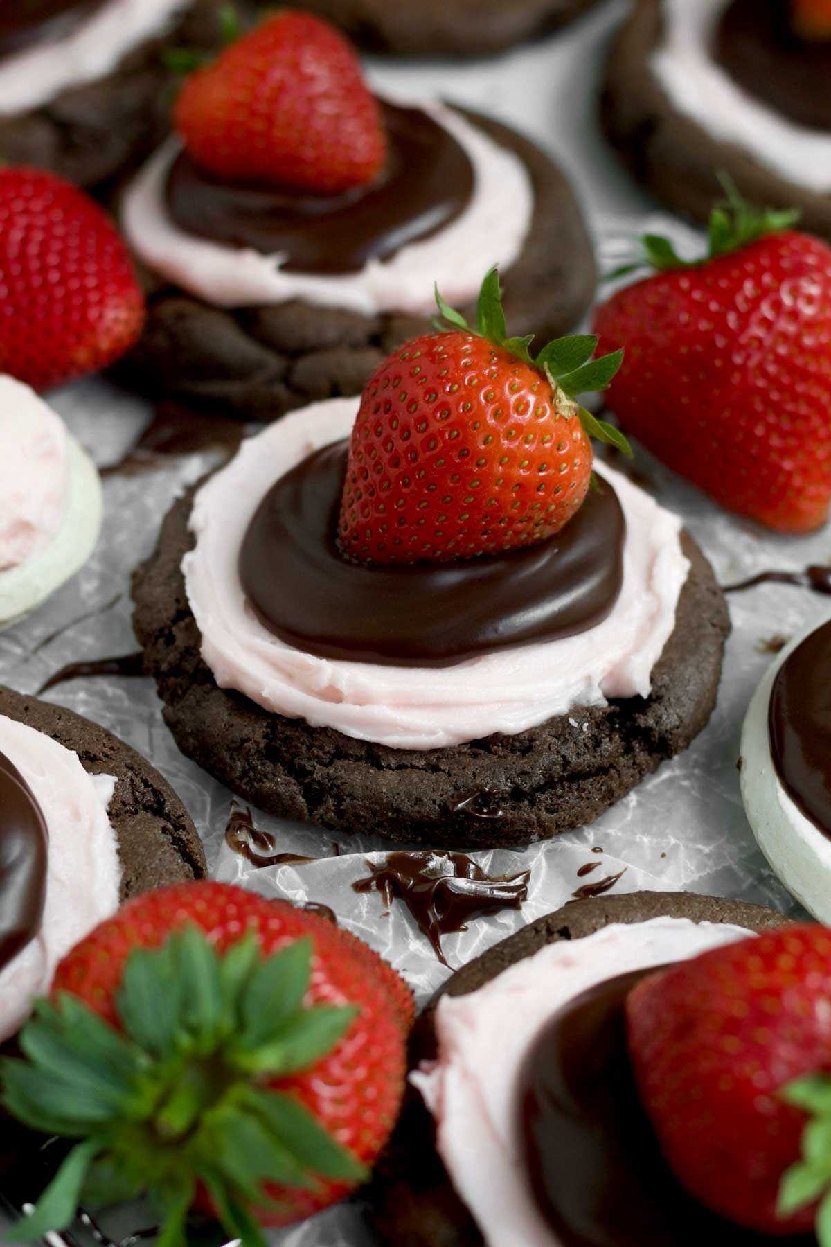 A strawberry held firm by hardened chocolate ganache on top off sweet strawberry buttercream on the cookie.