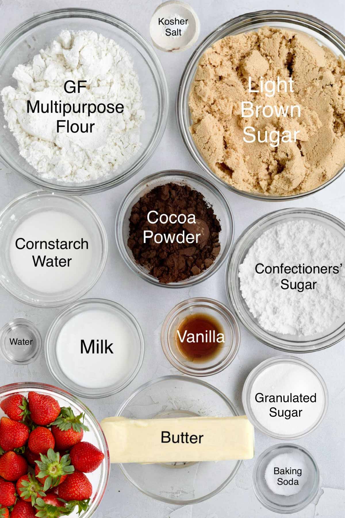 Bowls of gluten free flour, kosher salt, light brown sugar, cornstarch water, cocoa powder, confectioners' sugar, water, milk, vanilla, granulated sugar, strawberries, butter and baking soda.