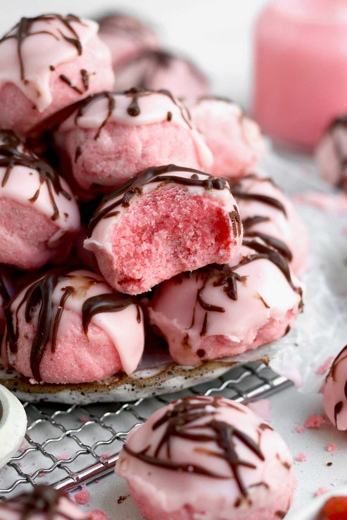 Pile of Strawberry Shortbread Cookies with one missing a bite exposing its lite and sugary interior.